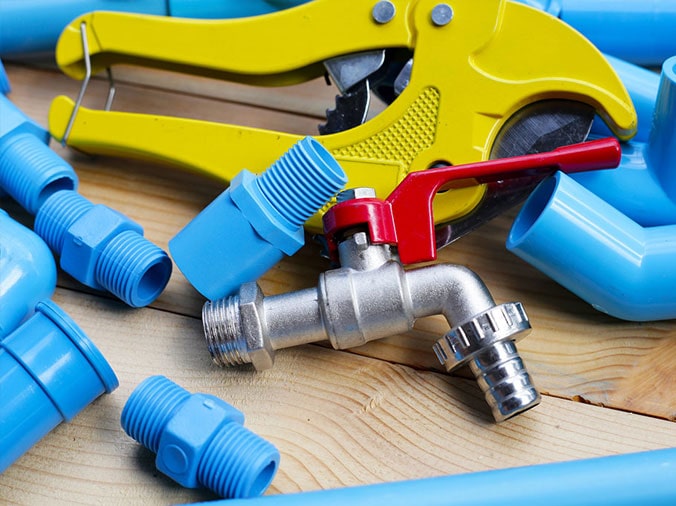 Blue PVC fittings with a PVC cutting tool and a steel plumbing valve